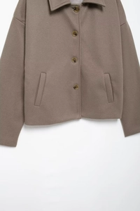 Detail of brown wool jacket featuring a lapel collar, four buttons and side pockets