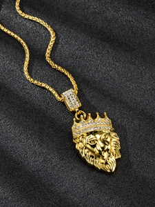 Close-up of golden lion head pendant with crown and rhinestones on black background