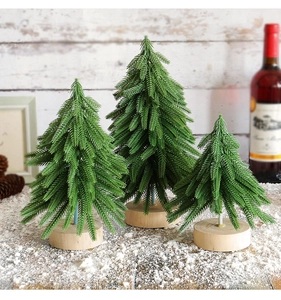 Three mini artificial Christmas trees on wooden bases with faux snow and pine cones