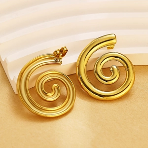 Vue macro de boucles d'oreilles spirales dorées au fini brillant sur fond à textures ondées