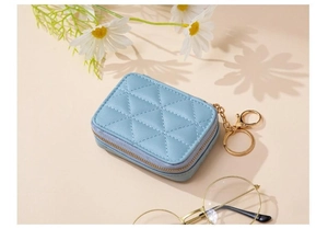 Detail of light blue quilted PU leather mini cosmetic pouch with gold metal keychain