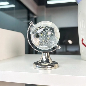 Minimalist transparent crystal globe ornament on a silver metal stand for desk decor