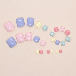 Flat lay of colorful rainbow press-on toenails in pastel macaron shades on a beige background