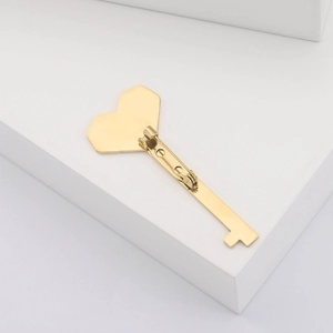 Detail of creative gold heart key brooch with polished metallic finish on white background