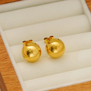 Minimalist gold dome stud earrings made of smooth stainless steel in a beige jewelry box