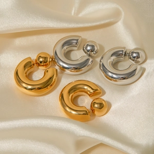 Chunky 16k gold and silver stainless steel C-shaped hoop earrings on silk background