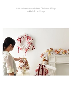 Cozy white Christmas wreath and mini tree decor set with red bows on an elegant fireplace