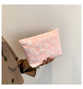 Detail of pink clutch bag featuring 3D white floral embossed texture and premium finish