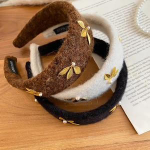 Detailed macro view of plush velvet headbands with golden leaves and pearl accents