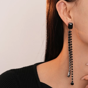Detail of long black fringe earrings with rhinestones on a model in dark gothic style