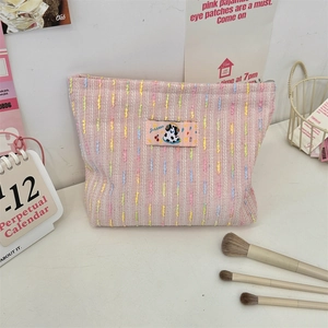 Détail de la trousse de maquillage en tweed rose avec tissage et écusson chien