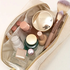 Spacious beige corduroy makeup bag with gold zipper showing cosmetics and brushes