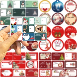 Detail of Christmas gift labels held in hand showing various Santa and Reindeer designs