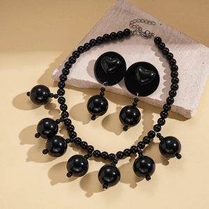 Exaggerated black acrylic beaded necklace and heart earring set on stone display