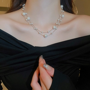 Close-up of elegant gold plated layered necklace featuring irregular white pearls on a model