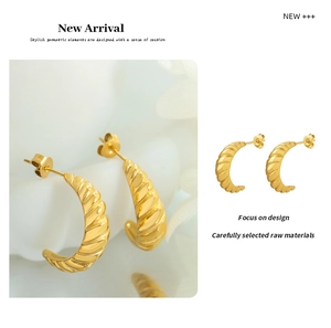 Makroaufnahme vergoldeter Croissant-Ohrringe mit eleganter, spiralförmiger Textur