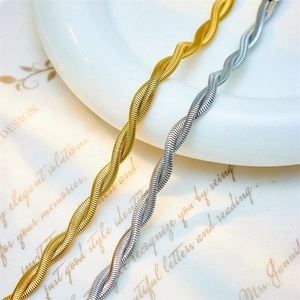 Punk style titanium steel twisted chain bracelets in gold and silver on a ceramic plate