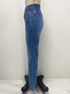 Detail of high waisted blue denim jeans featuring elastic waistband and button fly closure