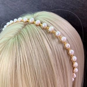 Elegant gold metal crown headband with white pearls shown on a mannequin head