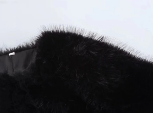 Close-up of black faux fur texture showing fluffy long fibers of a luxury jacket