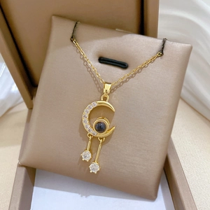 Detail of gold crescent moon pendant with sparkling zircons and hanging round stones