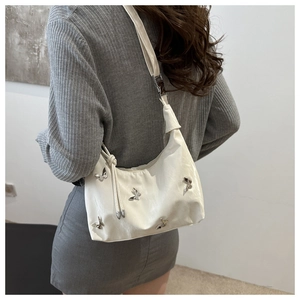Chic white shoulder bag with silver butterfly charms worn by a model in a trendy outfit