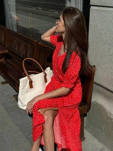 Detail of red polka dot dress with V-neck, puff sleeves and elegant side slit design
