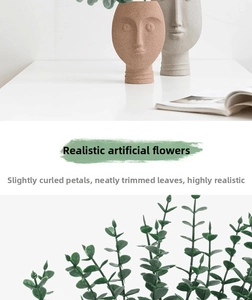 Detailed close-up of lifelike green eucalyptus leaves in Nordic face-shaped ceramic vases