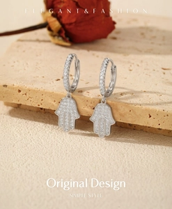 Vue macro des boucles d'oreilles Main de Hamsa en argent avec zircons sur pierre rustique
