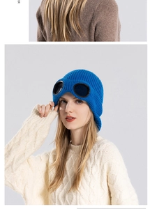 Detailed close-up of blue knitted beanie with integrated black goggles on a model