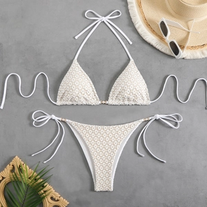 Detail of white crochet bikini set with halter top, side ties and elegant pearl accents