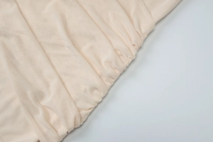 Detailed macro shot of beige mesh fabric texture with elegant pleated and elastic folds