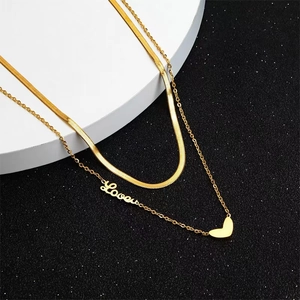 Détail du collier double rang en acier titane doré avec pendentif Love et petit cœur