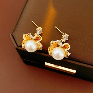 Dettaglio di orecchini a foglia di ginkgo dorati con perle bianche e zirconi scintillanti