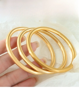 Detailed close-up of three gold satin finish bracelets worn on a wrist for daily styling