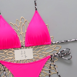 Close-up of pink bikini top with leopard print straps and decorative card on flat lay