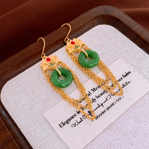 Macro view of gold ear hooks with green jade-like circle and elegant chain tassels