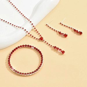 Elegant red rhinestone jewelry set featuring a silver necklace, bracelet, and drop earrings