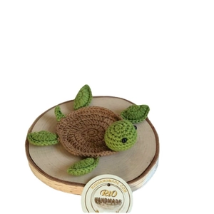 Handmade crochet turtle coaster with textured brown shell on a natural wood base