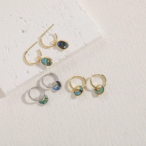 Detail of three pairs of abalone shell earrings in gold and silver finish on stones