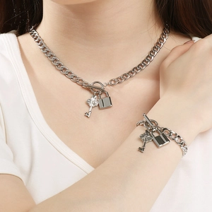 Gros plan d'un ensemble collier et bracelet argenté avec pendentifs clé et cadenas sur mannequin