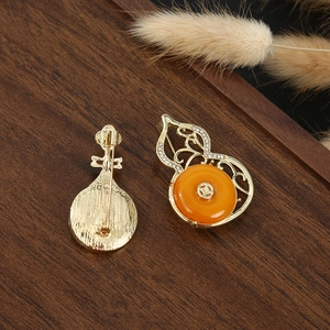 Macro detail of Chinese style gourd and pipa brooches with orange agate on wood