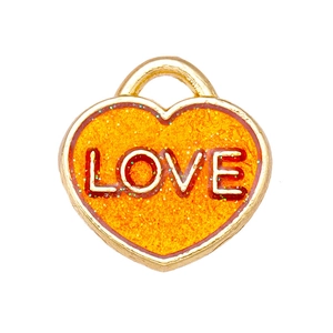 Macro detail of heart charm with gold frame and sparkling orange sequins with LOVE text