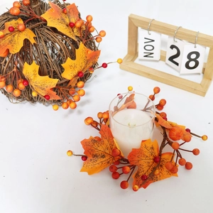 Detail of harvest candle ring with maple leaves, red berries and a glass holder