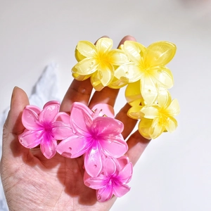Detail shot of matte pink and yellow flower hair claws held in hand for hair styling