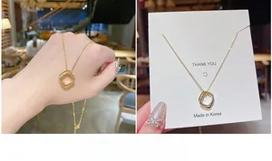 Dettaglio di collana in titanio placcata oro con ciondolo quadrato in stile minimal