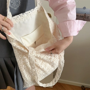 Detailed view of white floral lace tote bag featuring inner lining and zipper pocket
