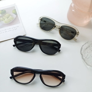 Three pairs of vintage oval sunglasses displayed with a pink vase and fruit card