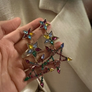 Detailed close-up of gold star earrings featuring multi-color sparkling crystal gemstones