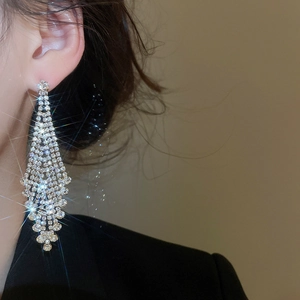 Nahaufnahme eleganter langer Quasten-Ohrringe aus Silber mit Strasssteinen am Model